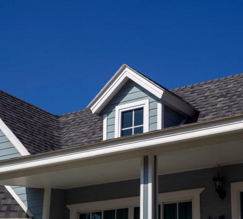 White vintage windows, little room decoration on the roof of the big wooden house pastel green color on blue sky background, view from outside.